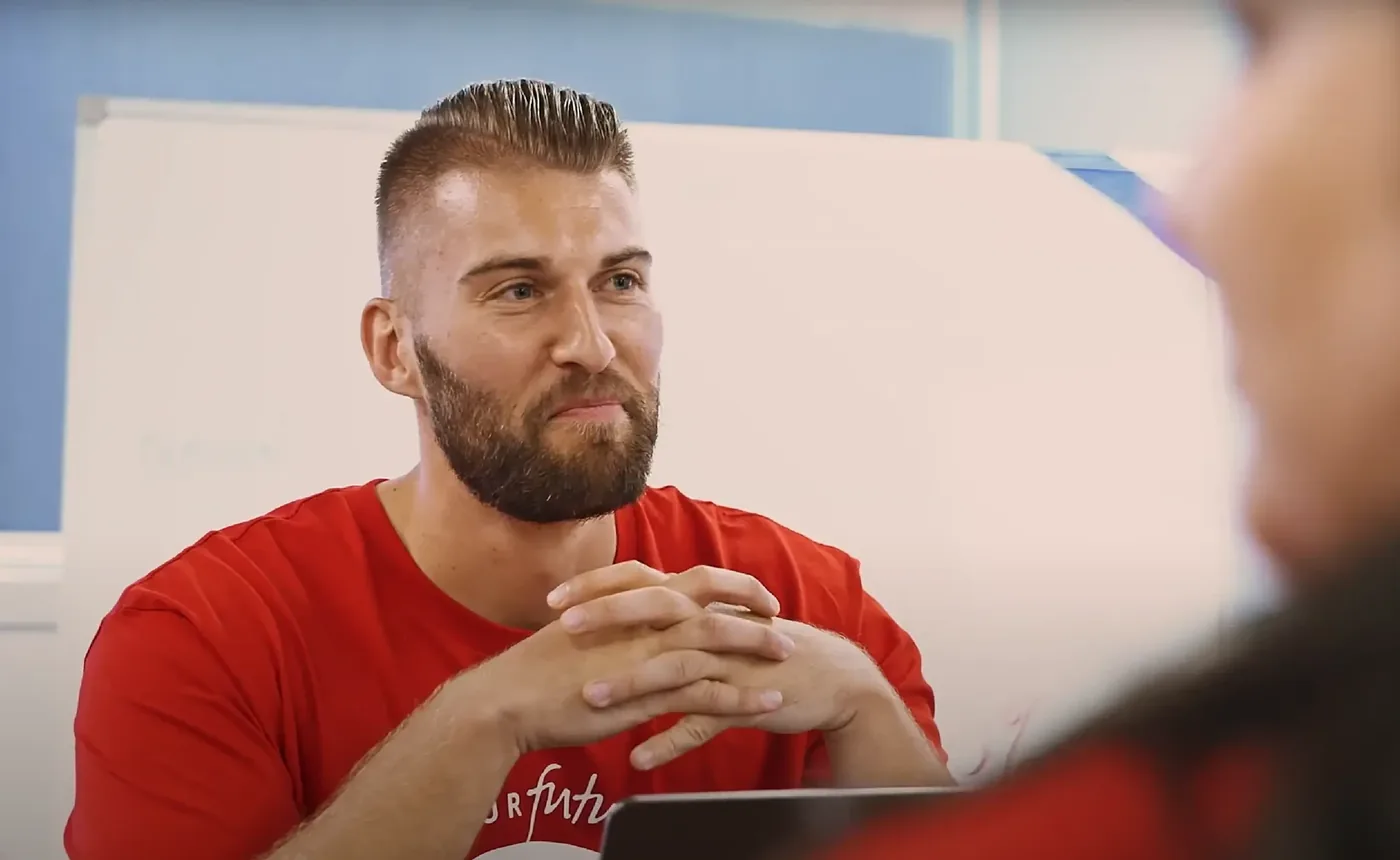 Asher in a team workshop, hands clasped, listening